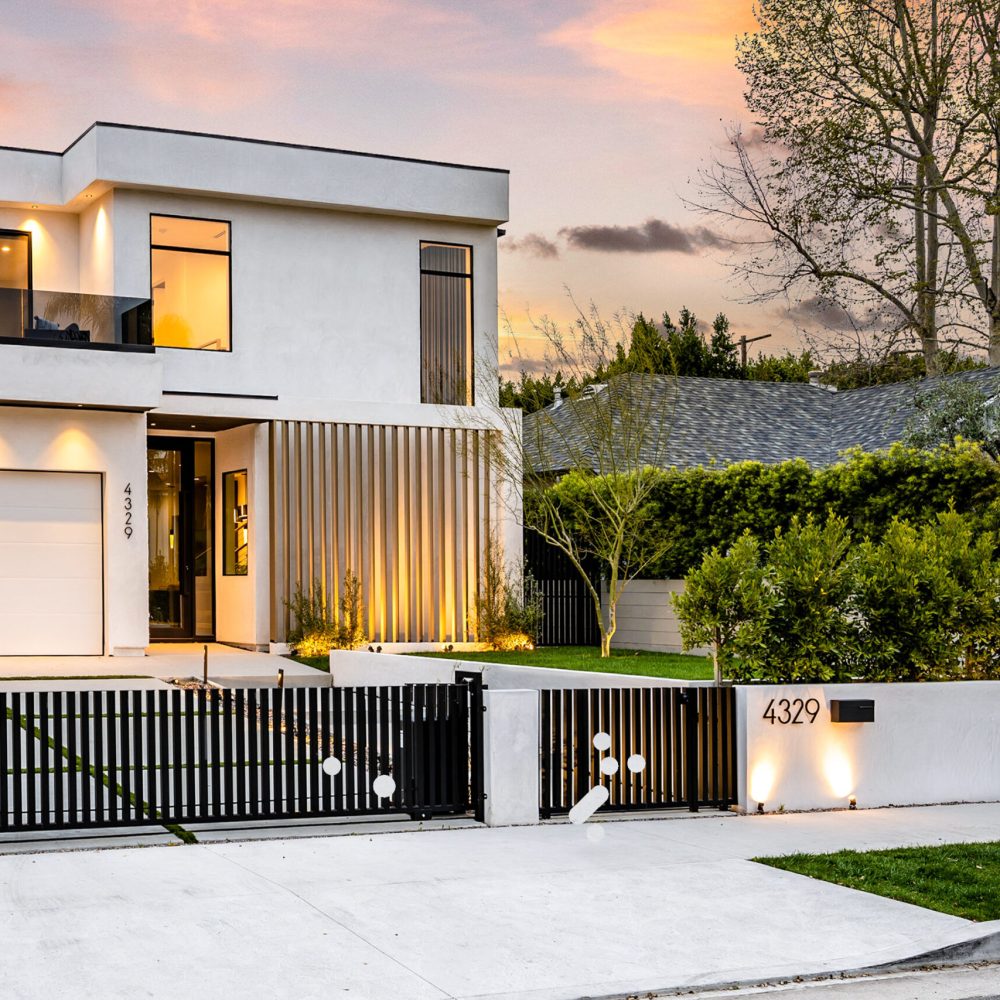 A large white house with a charming gate surrounded by trees